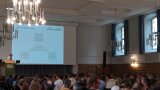 Personen in einem Saal, an Wand Leinwand