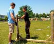 2 Personen stehen neben einem senkrechten Holzbalken