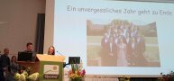 Personen stehen am Rednerpult