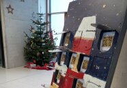 Adventskalender mit mehreren geöffneten Türchen, dahinter Christbaum