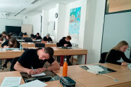 Personen sitzen an Tischen in einem Klassenzimmer