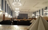 Saal mit Tischen und Stühlen, im Vordergrund Servietten