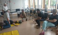 Mehrere Personen in einem Raum; eine Person liegt am Boden, weitere kniet daneben