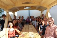 PErsonen sitzen an Holztisch in einer Holzhütte
