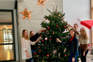 5 Personen stehen um einen Christbaum in einer Eingangshalle