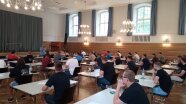 Personen an Tischen in einem Saal